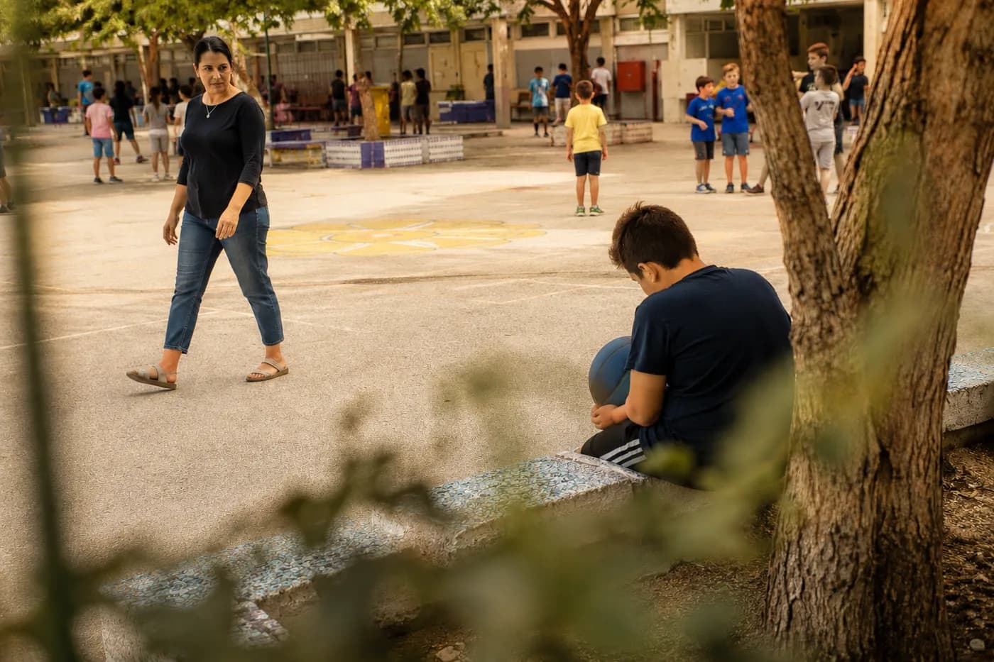 אשת צוות חינוכי בחצר בית הספר מבחינה בילד שיושב לבדו
